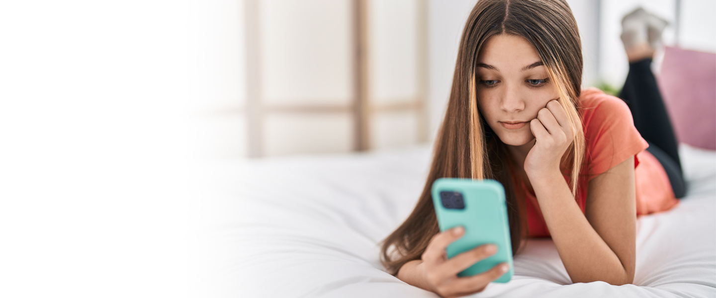 Young person on their mobile phone in their bedroom